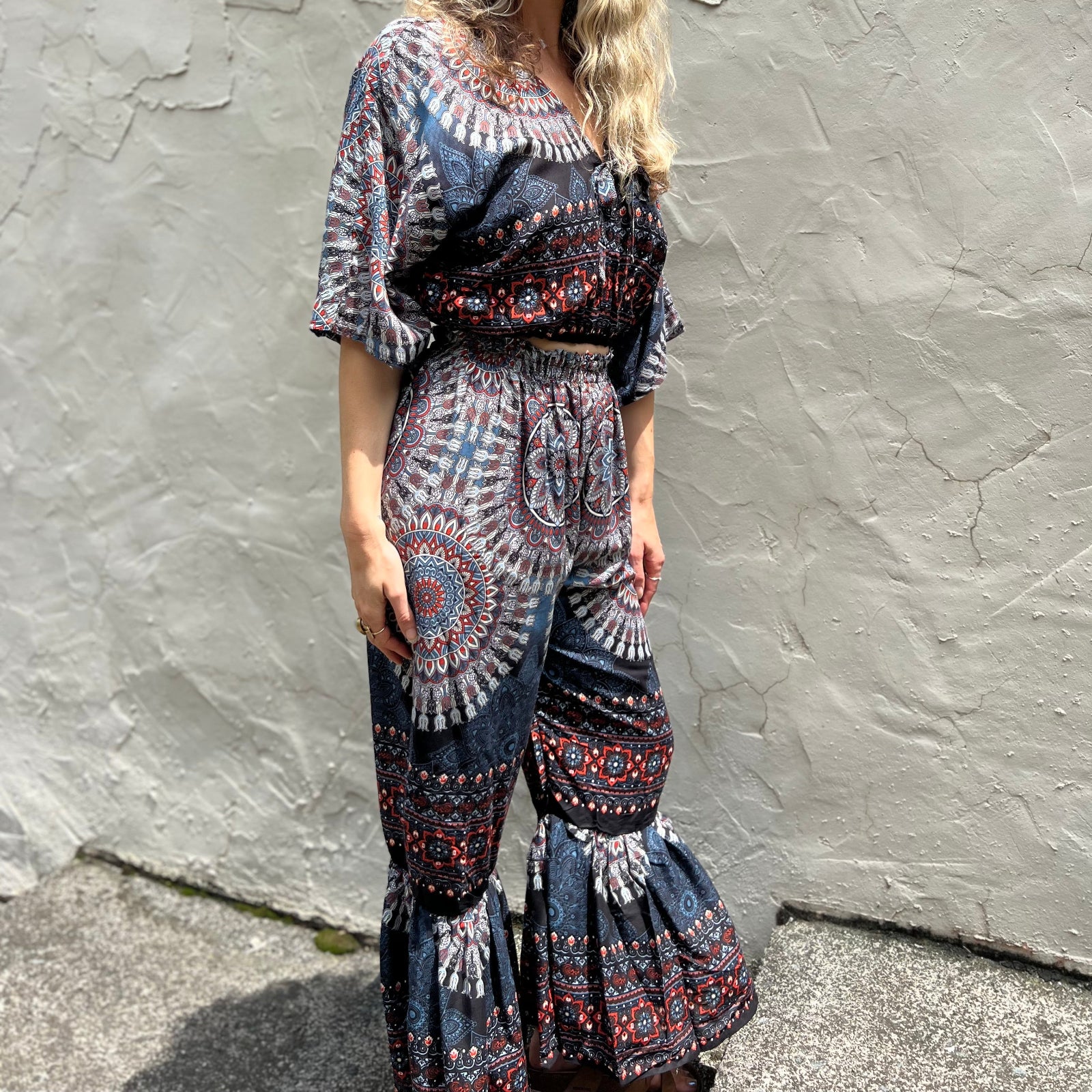 A woman wearing the blue Woven Floral Paisley Top and Trouser Set in front of a white wall.