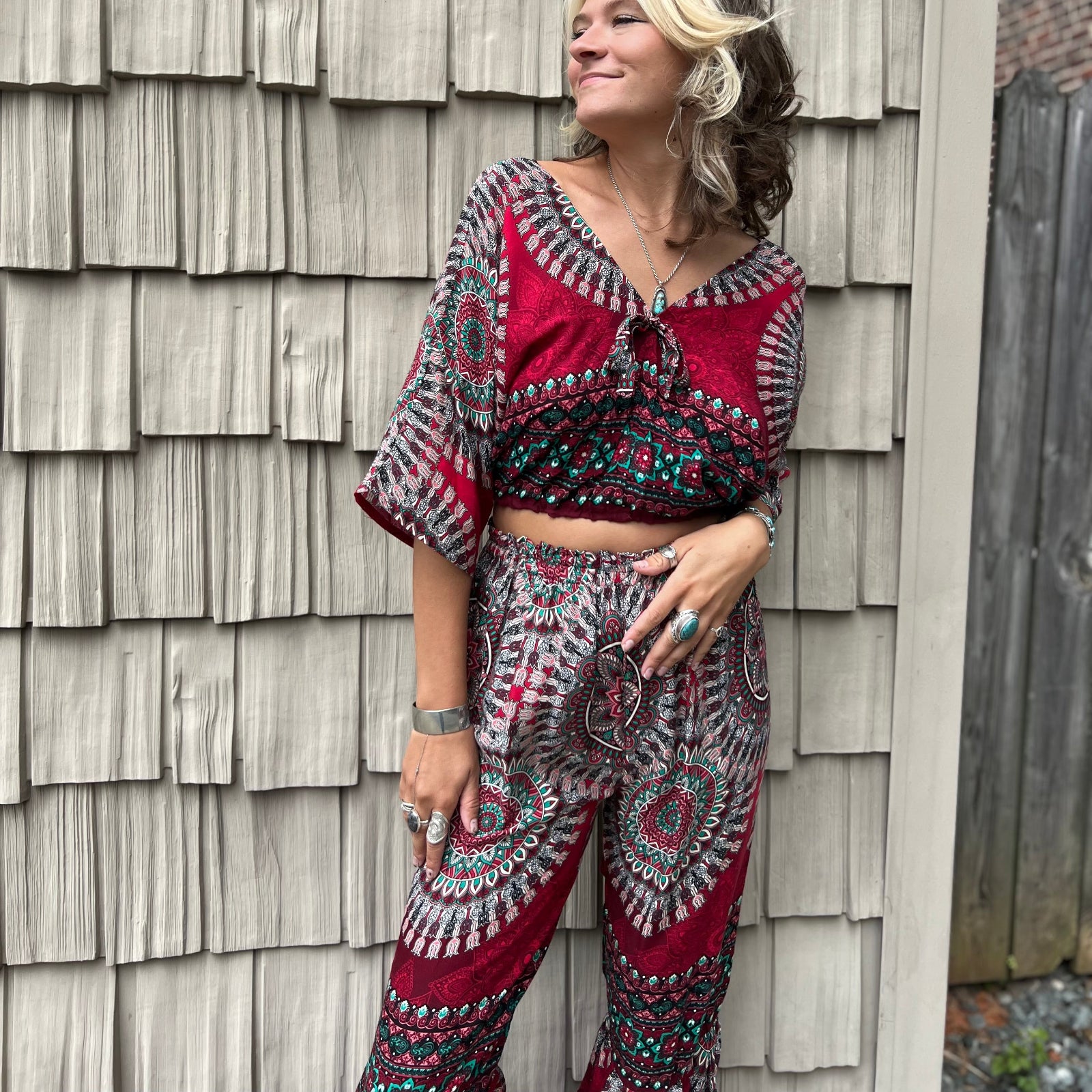 A woman wearing the pink Woven Floral Paisley Top and Trouser Set in front of a white wall.