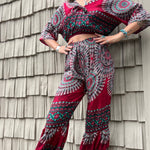 A woman wearing the pink Woven Floral Paisley Top and Trouser Set in front of a white wall.