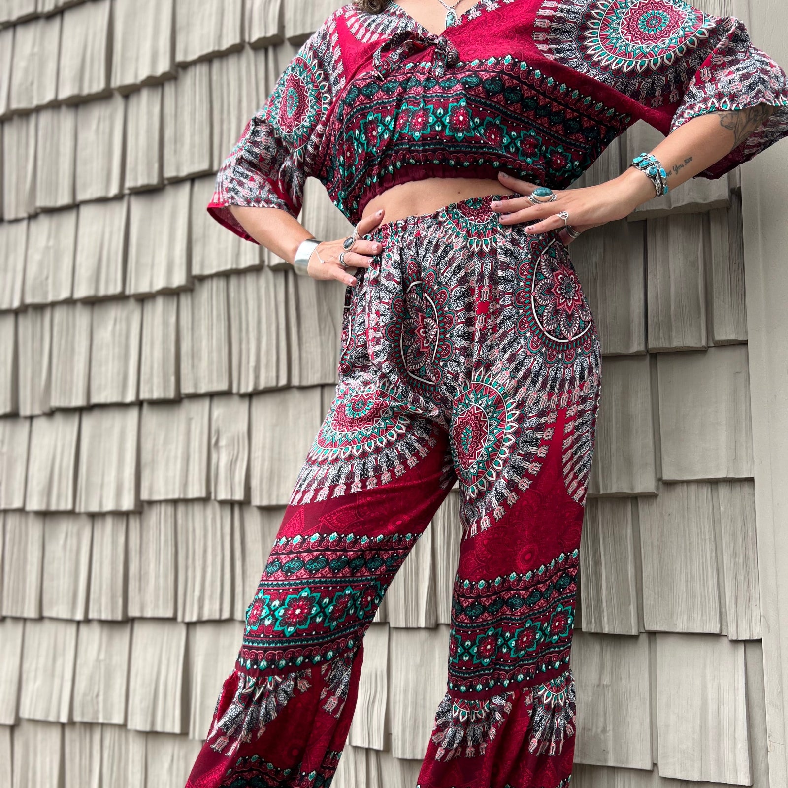 A woman wearing the pink Woven Floral Paisley Top and Trouser Set in front of a white wall.
