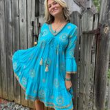 A woman wearing the Cotton Crepe Lace Embroidery Turquoise Dress in front of a wooden fence.