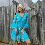 A woman wearing the Cotton Crepe Lace Embroidery Turquoise Dress in front of a wooden fence.