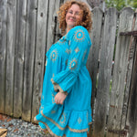 A woman wearing the Cotton Crepe Lace Embroidery Turquoise Dress in front of a wooden fence.