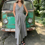 A woman wearing the Grey Striped Palazzo Cotton Jumpsuit in front of a vintage Volkswagen bus.