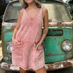 A woman wearing the Pink Garment Washed Cotton Denim Overall Dress in front of a vintage teal Volkswagen bus.