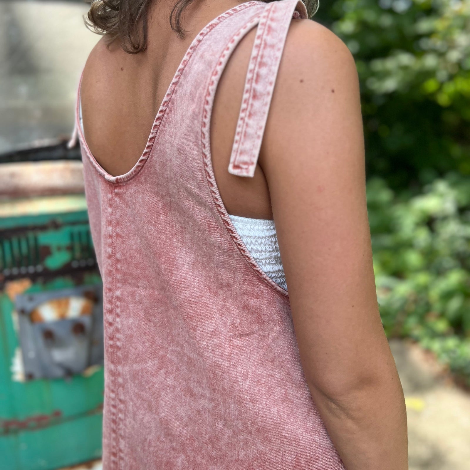 A woman wearing the Pink Garment Washed Cotton Denim Overall Dress in front of a vintage teal Volkswagen bus.