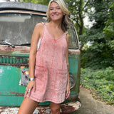 A woman wearing the Pink Garment Washed Cotton Denim Overall Dress in front of a vintage teal Volkswagen bus.