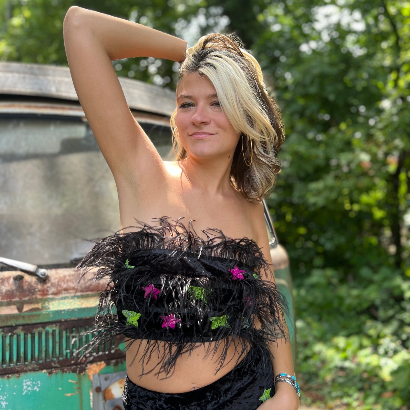 A woman wearing the black Feather Crop Top with Stretch Flared Pants Set in front of a vintage teal Volkswagen bus.