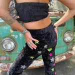 A woman wearing the black Feather Crop Top with Stretch Flared Pants Set in front of a vintage teal Volkswagen bus.