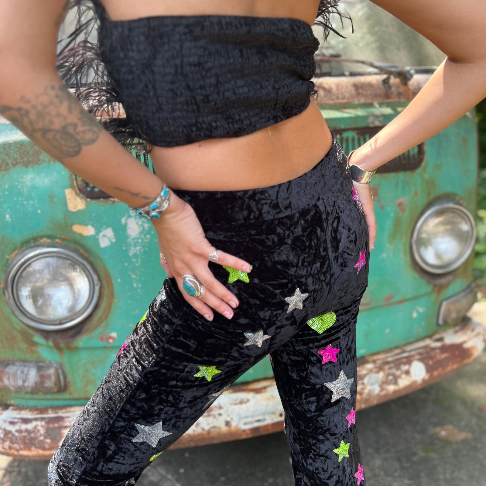 A woman wearing the black Feather Crop Top with Stretch Flared Pants Set in front of a vintage teal Volkswagen bus.