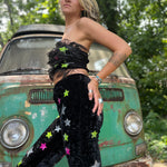 A woman wearing the black Feather Crop Top with Stretch Flared Pants Set in front of a vintage teal Volkswagen bus.