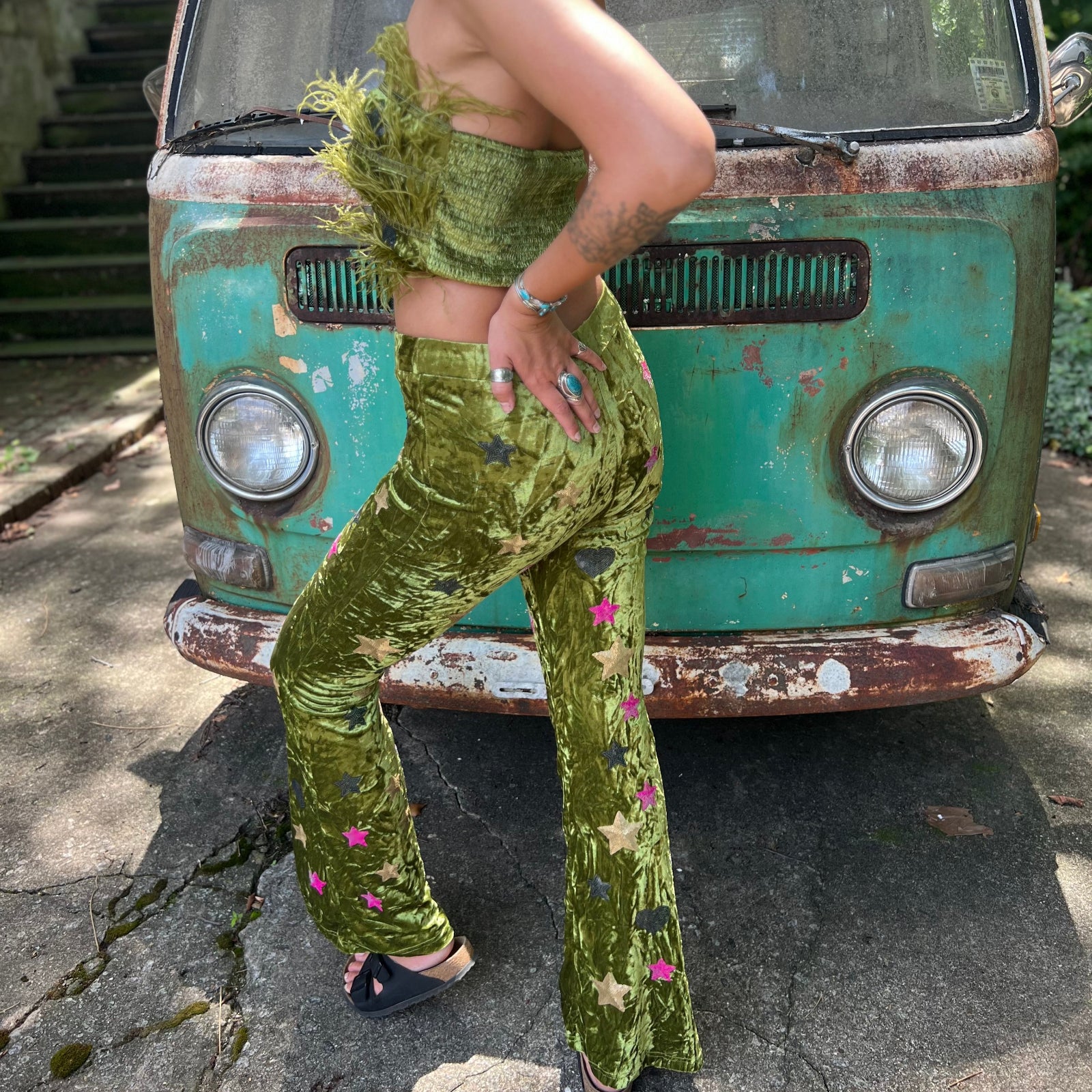 A woman wearing the moss green Feather Crop Top with Stretch Flared Pants Set in front of a vintage teal Volkswagen bus.