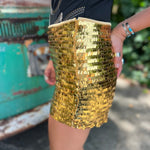 Someone wearing the Gold Sequin Fitted Hot Shorts with a black top in front o f a vintage Volkswagen bus.