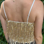 A woman wearing the gold Sequin Tiered Fringe Cami Tank in front of a teal vintage Volkswagen bus.