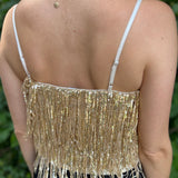 A woman wearing the gold Sequin Tiered Fringe Cami Tank in front of a teal vintage Volkswagen bus.
