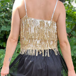 A woman wearing the gold Sequin Tiered Fringe Cami Tank in front of a teal vintage Volkswagen bus.