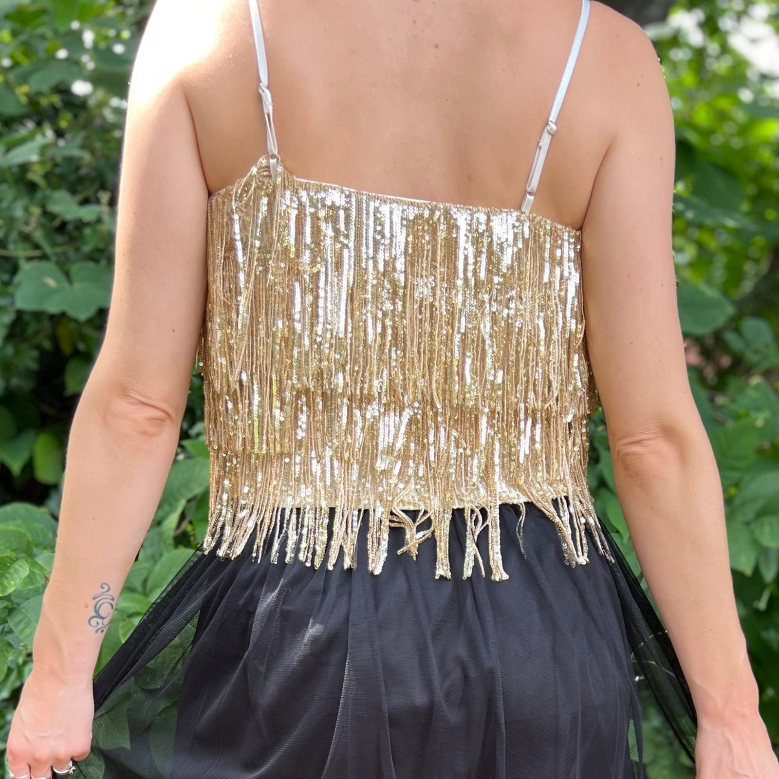A woman wearing the gold Sequin Tiered Fringe Cami Tank in front of a teal vintage Volkswagen bus.