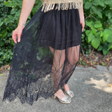 A woman wearing the Sheer Mesh Lace Mini Lined Maxi Skirt with a gold top in front of some greenery.
