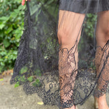 An up-close image of a woman wearing the Sheer Mesh Lace Mini Lined Maxi Skirt in front of some greenery.