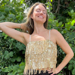 A woman wearing the gold Sequin Tiered Fringe Cami Tank in front of a teal vintage Volkswagen bus.