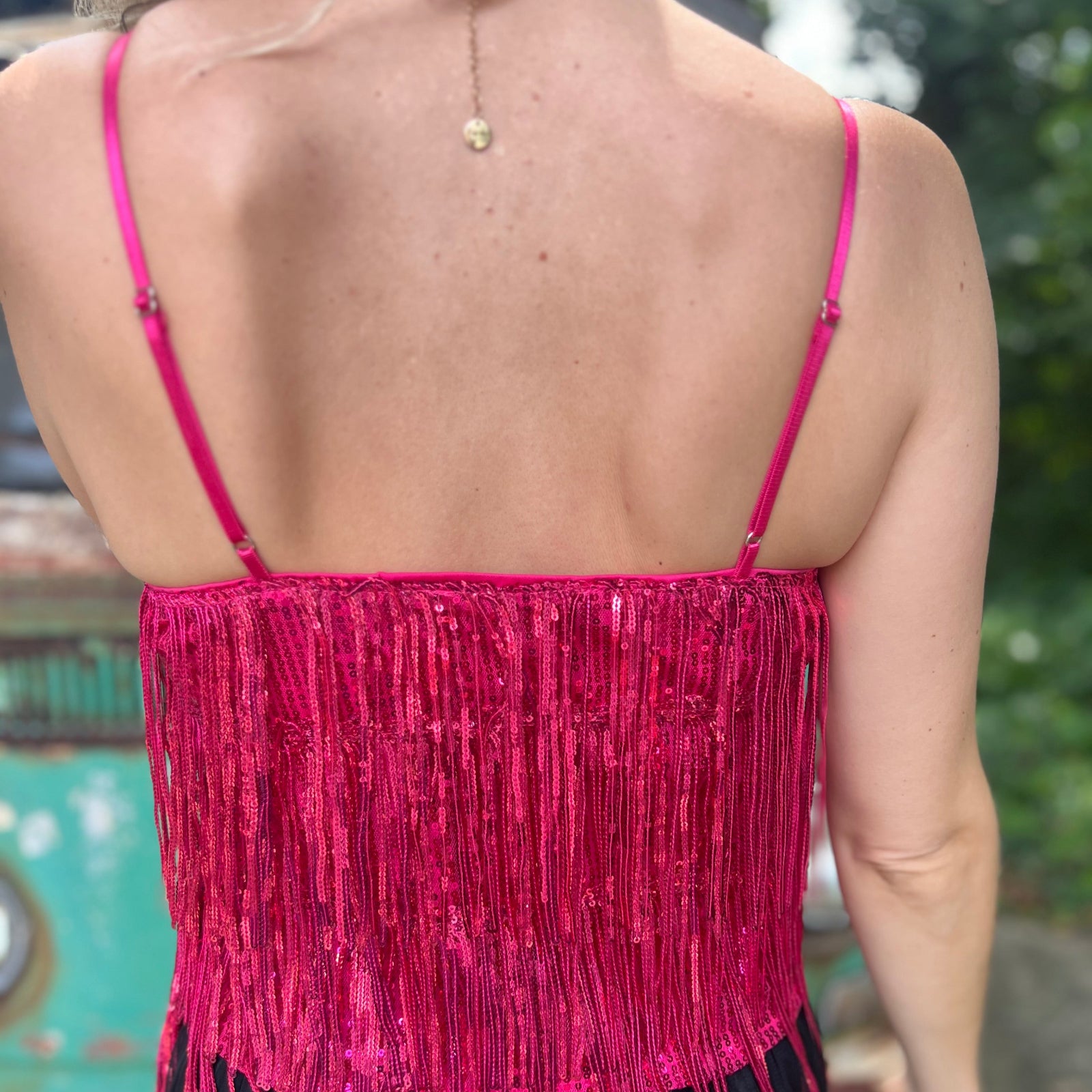 A woman wearing the hot pink Sequin Tiered Fringe Cami Tank in front of a teal vintage Volkswagen bus.