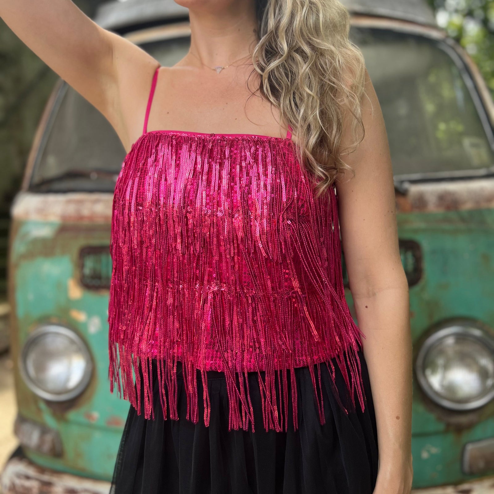 A woman wearing the hot pink Sequin Tiered Fringe Cami Tank in front of a teal vintage Volkswagen bus.