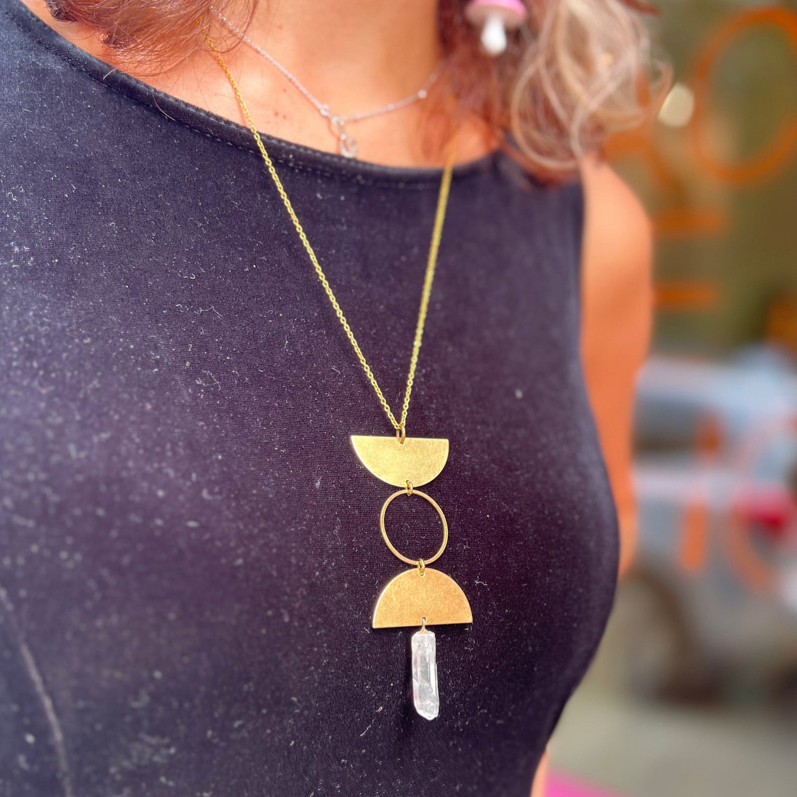 Someone wearing the Just a Phase Necklace with a black top.