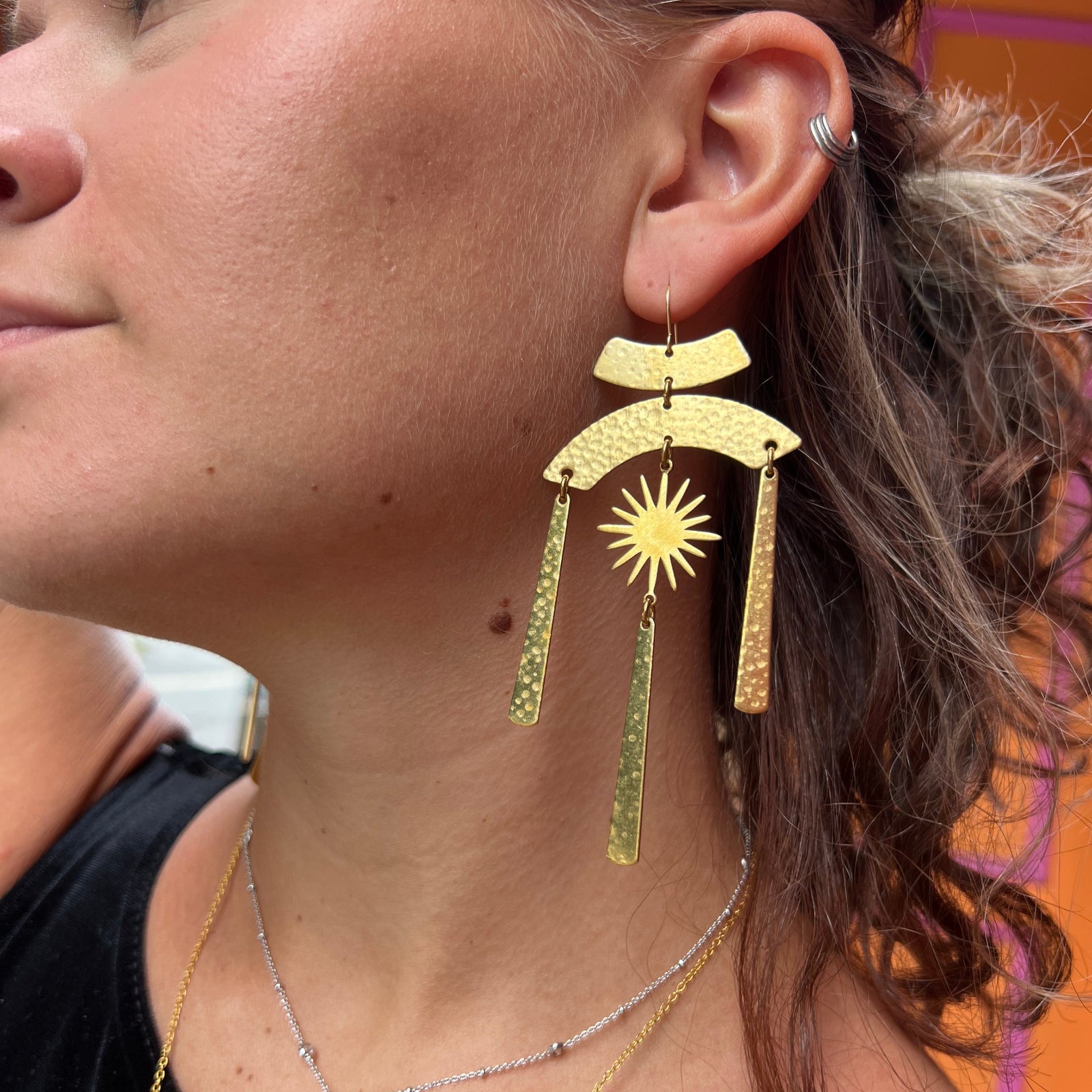 A woman wearing the Hammered Brass Summer Solstice 4 in. Earrings.
