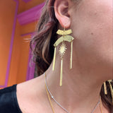 A woman wearing the Hammered Brass Summer Solstice 4 in. Earrings.