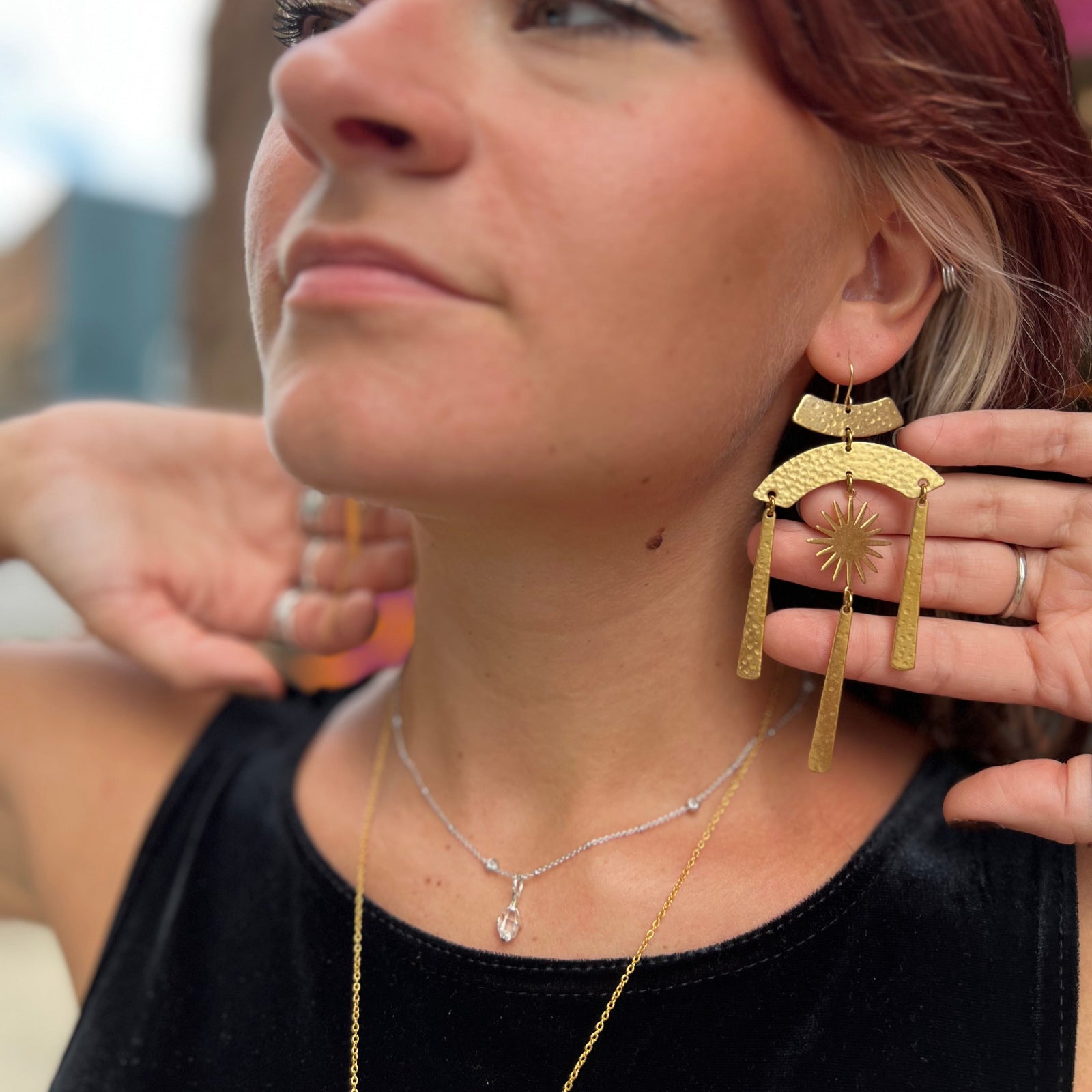 A woman wearing the Hammered Brass Summer Solstice 4 in. Earrings.