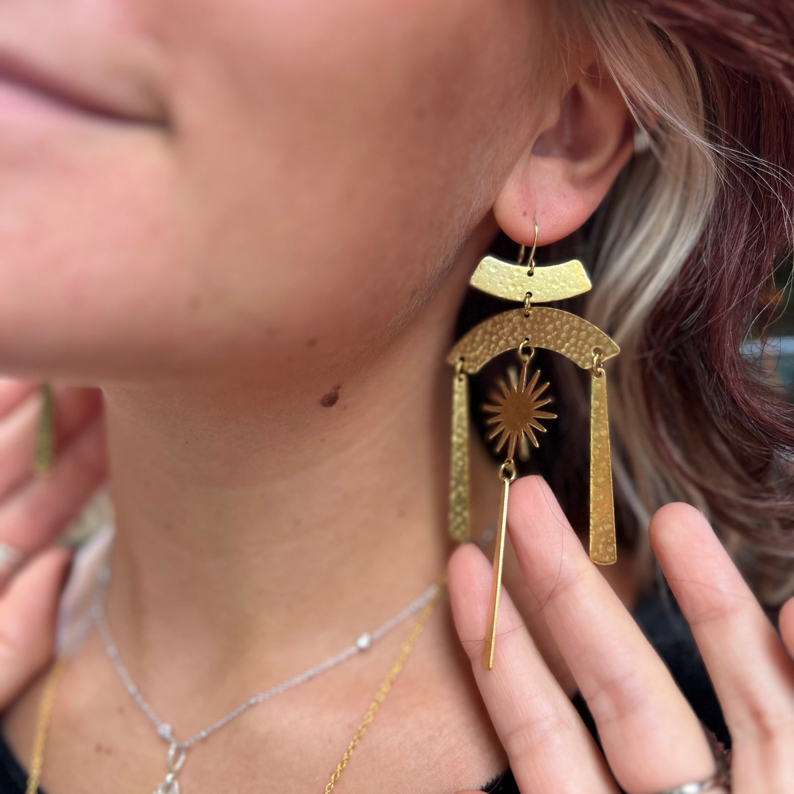 A woman wearing the Hammered Brass Summer Solstice 4 in. Earrings.