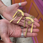 A woman holding the Hammered Brass Summer Solstice 4 in. Earrings.
