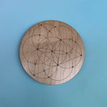 The Seed of Life 4 inch Wooden Crystal Grid on a light blue background.