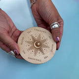 Someone holding the Moonlight Pendulum Wooden 4 inch Board in front of a blue background.