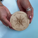 Someone holding the Moonlight Pendulum Wooden 4 inch Board in front of a blue background.