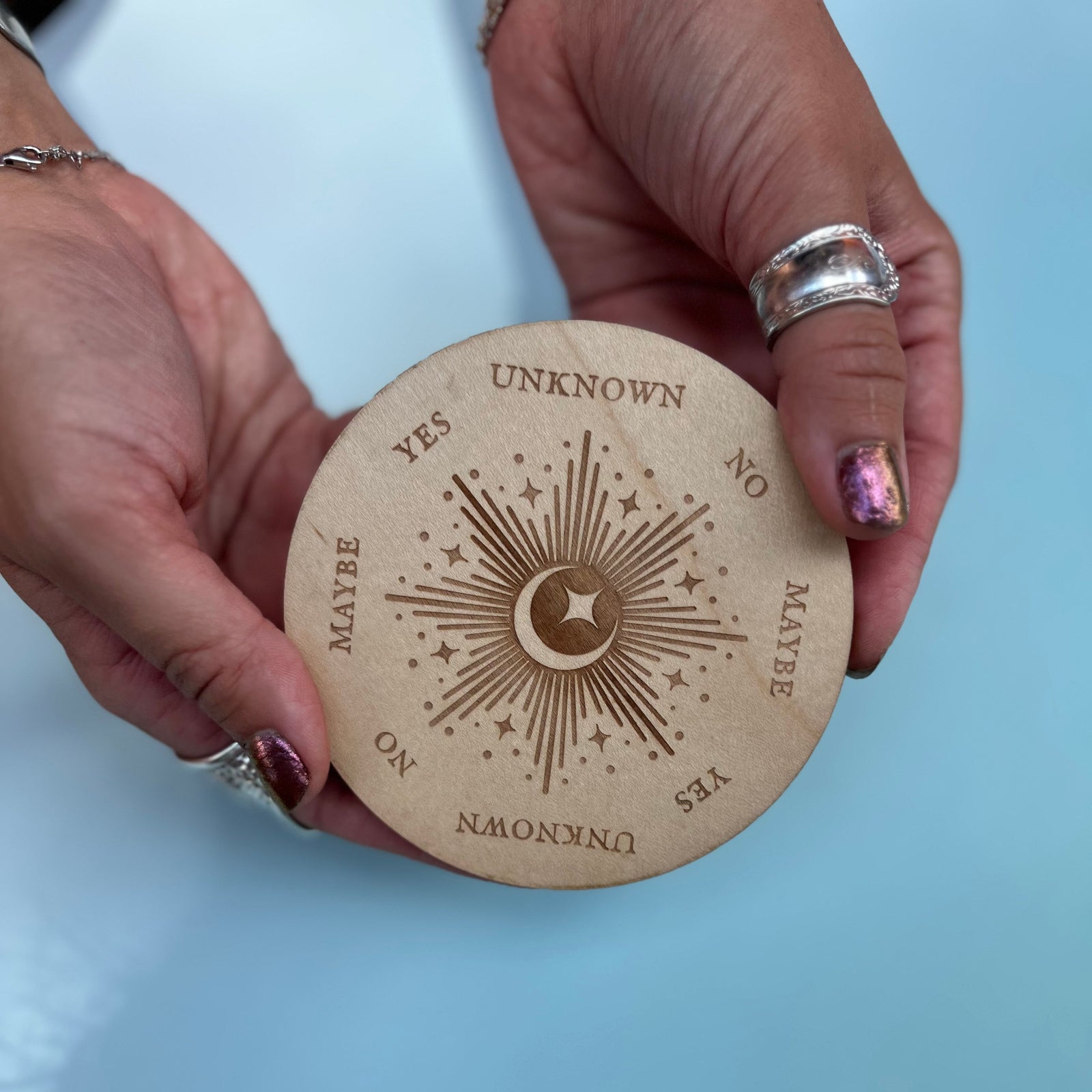 Someone holding the Moonlight Pendulum Wooden 4 inch Board in front of a blue background.