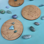 Three crystal grids with tumbled crystals on and around them, all on a light blue background.