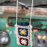 An up-close image of the Handmade Bohemian Crochet Phone Crossbody Bag in front of an old teal Volkswagen bus.