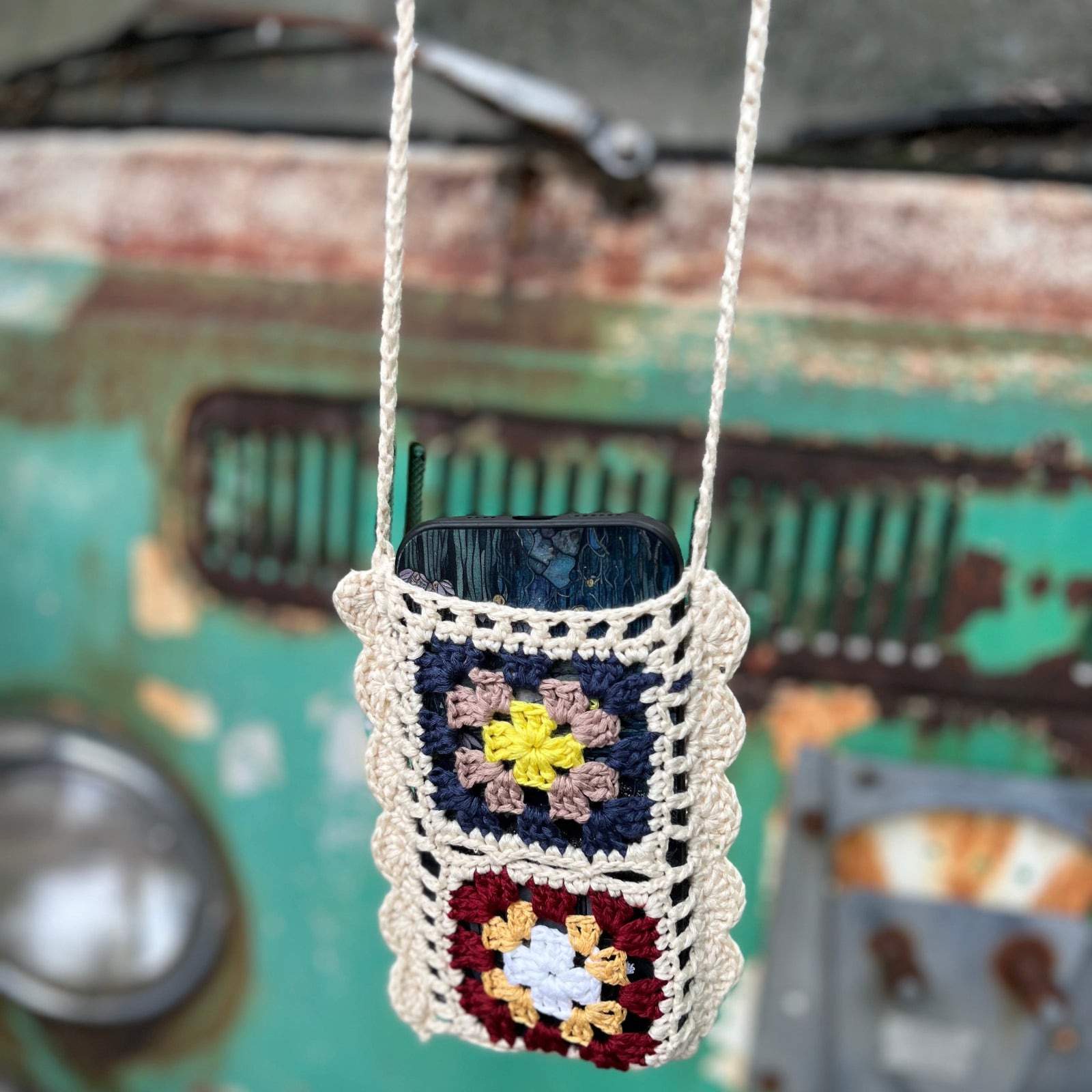 An up-close image of the Handmade Bohemian Crochet Phone Crossbody Bag in front of an old teal Volkswagen bus.