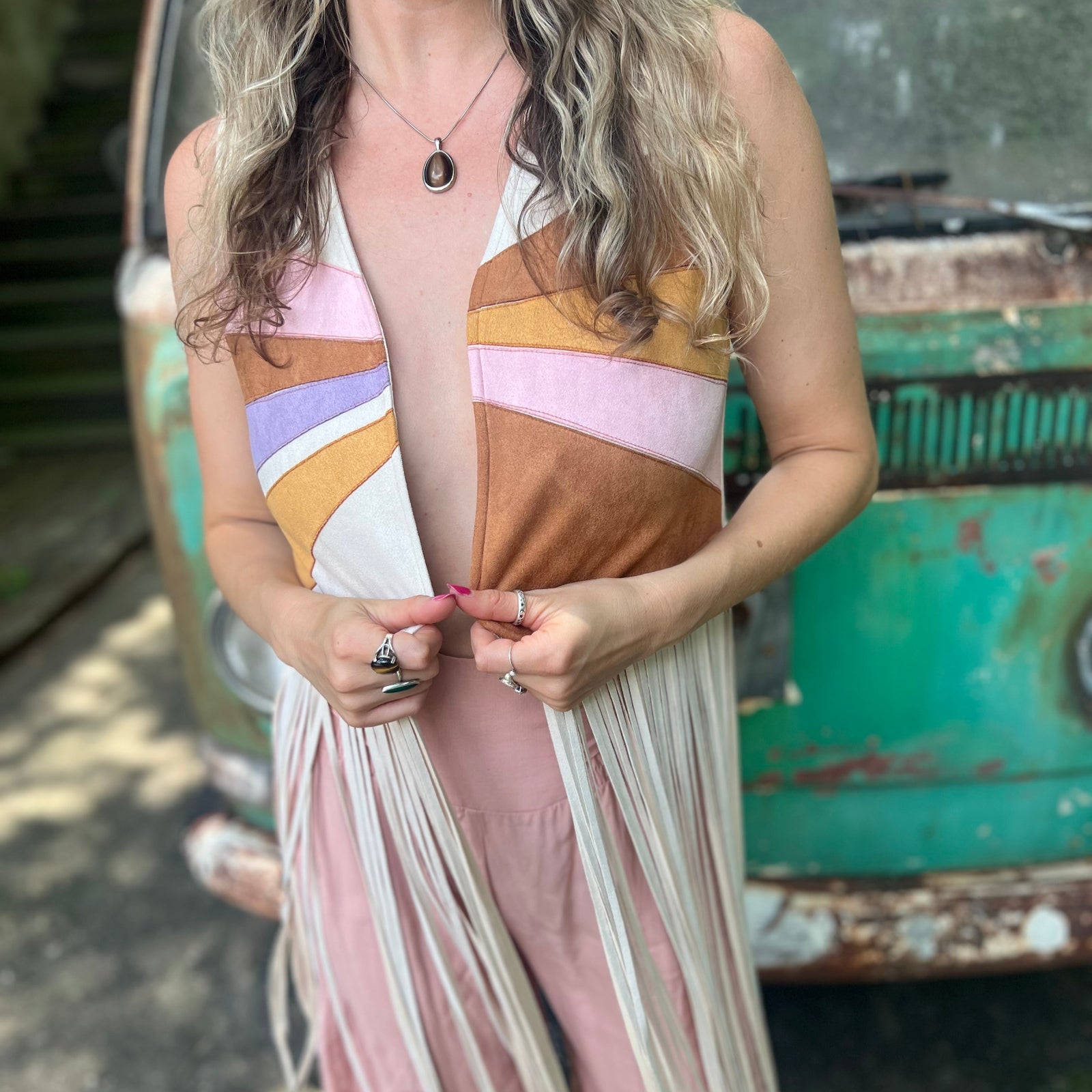A woman wearing the cream Retro Sunburst Suede Color Block Long Fringe Faux Vest.