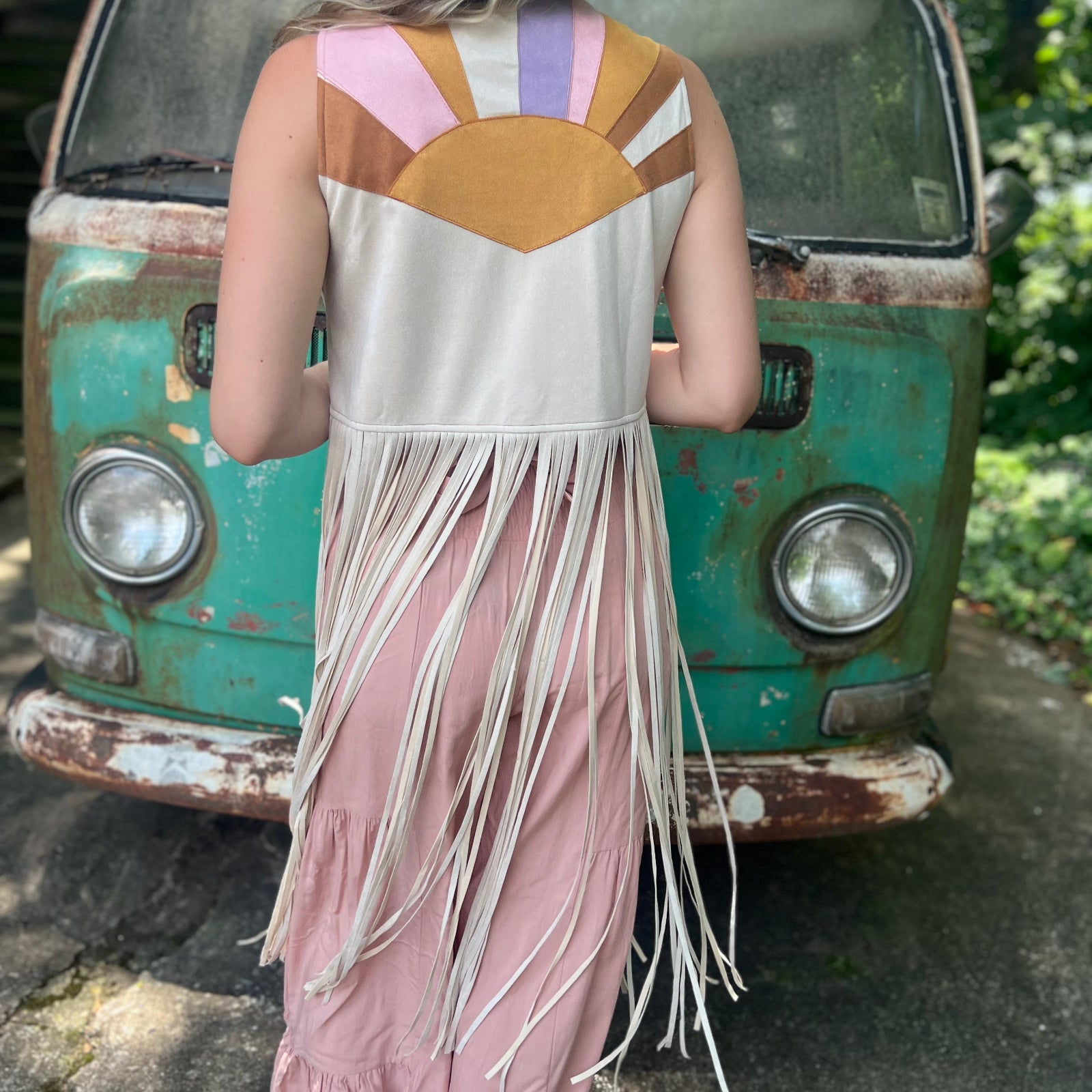 A woman wearing the cream Retro Sunburst Suede Color Block Long Fringe Faux Vest.