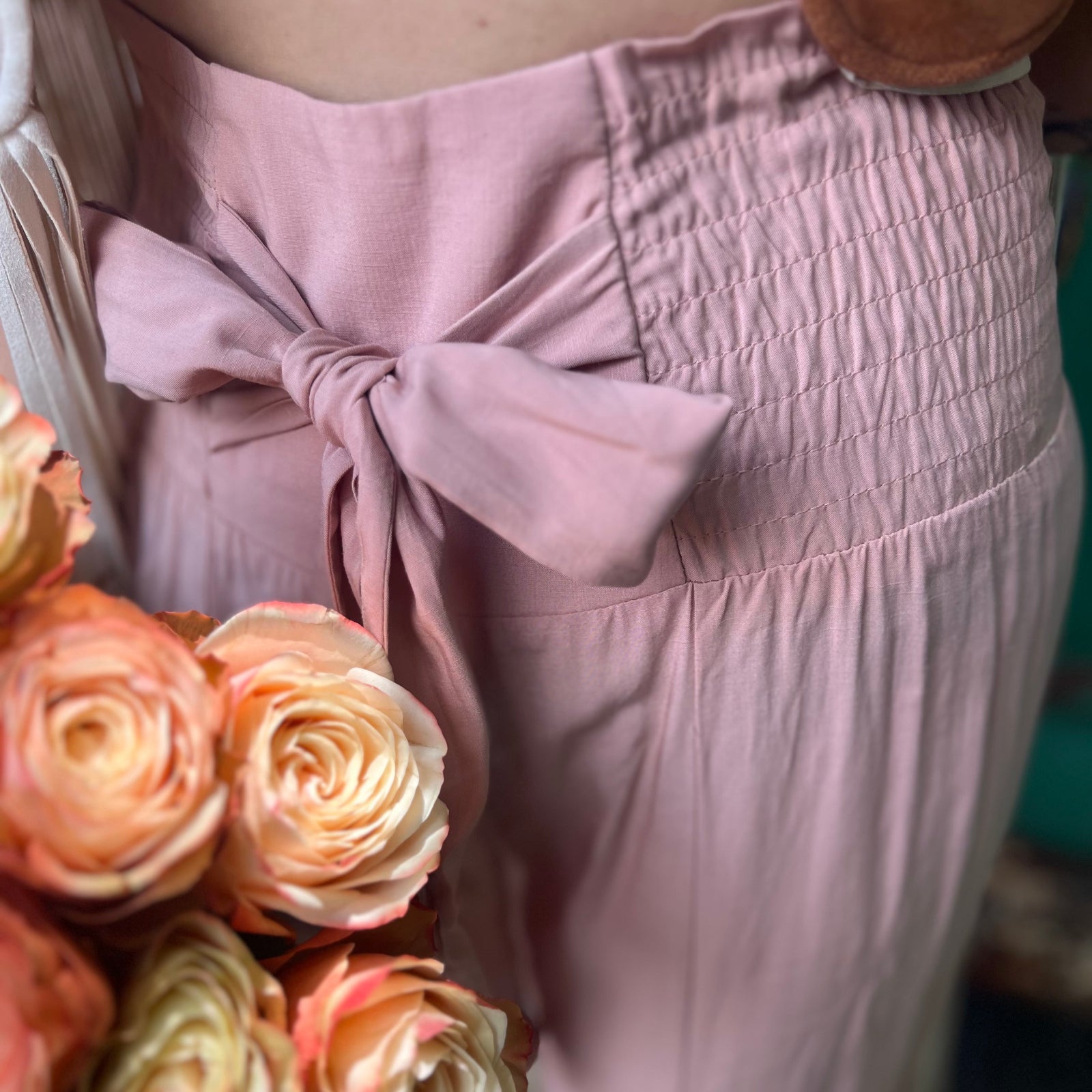 Someone wearing the mauve Smocking Waist Tier Wide Pants with flowers next to them.