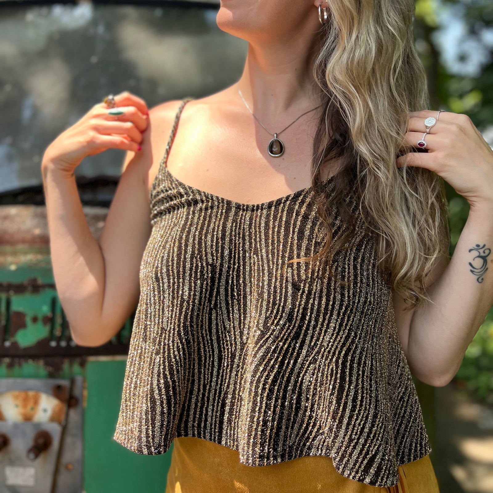 A woman wearing the Gold Spaghetti Strap Glitter Flowy Tank.