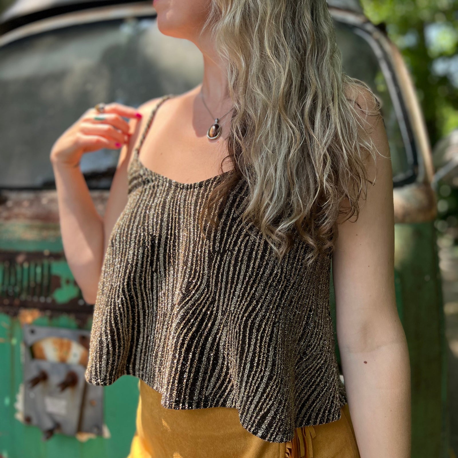 A woman wearing the Gold Spaghetti Strap Glitter Flowy Tank.