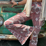 A woman wearing the Wine Western Paisley Print Fit & Flare Denim Jeans and cream fringe vest.