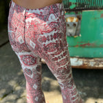 A woman wearing the Wine Western Paisley Print Fit & Flare Denim Jeans and cream fringe vest.