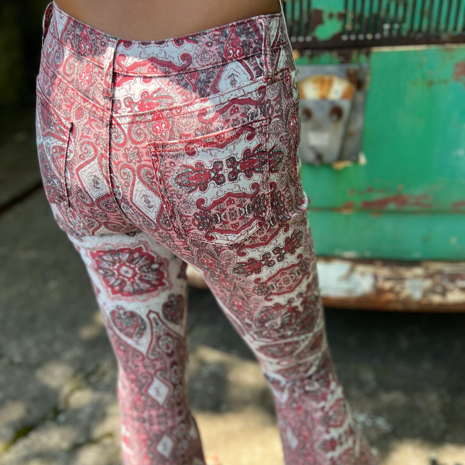 A woman wearing the Wine Western Paisley Print Fit & Flare Denim Jeans and cream fringe vest.