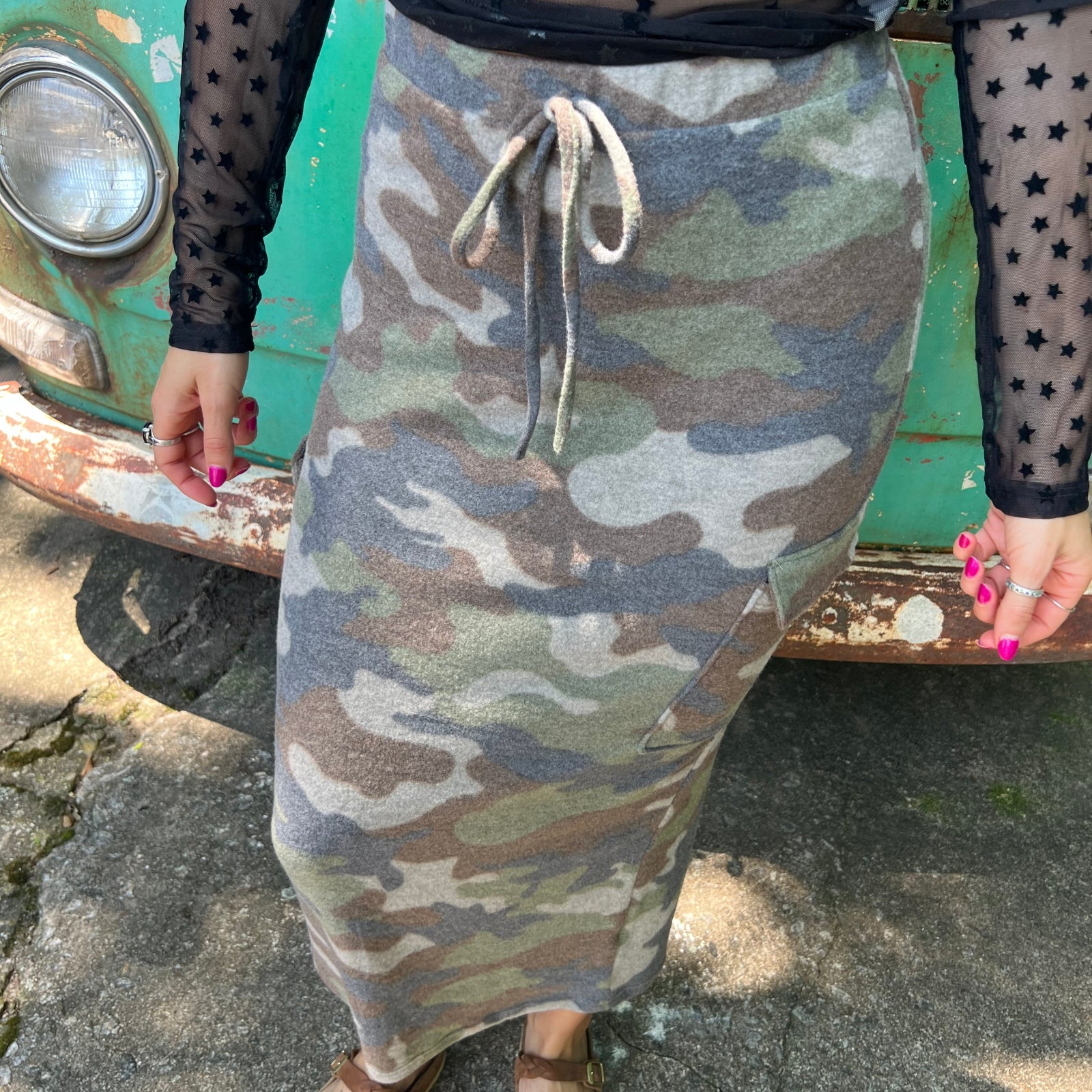 A woman wearing the Camo Cargo Skirt with a black star mesh top.