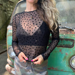 A woman wearing the Star Flocking Sheer Mesh Top and a camo skirt.