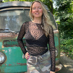A woman wearing the Star Flocking Sheer Mesh Top and a camo skirt.
